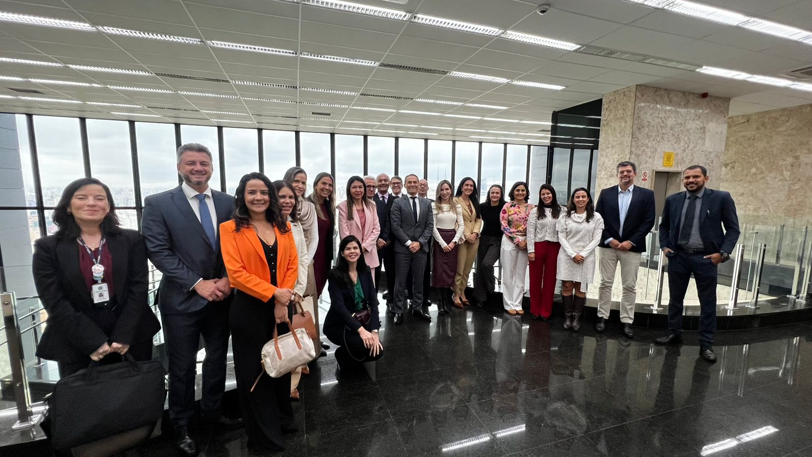 Fotografia com a presença de 21 pessoas, 13 mulheres e 8 homens, uma delas está abaixada e o restante está em pé.