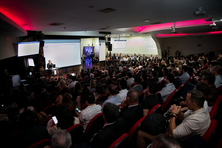 Fotografia da audiência assistindo a um seminário. 