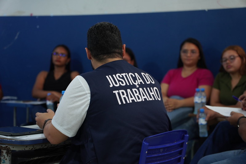 Homem com coleta da Justiça do Trabalho em uma sala com atendimento.