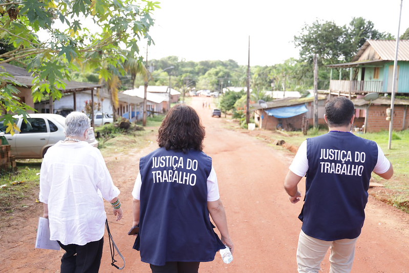 Pessoas com o colete da Justiça do Trabalho pelas ruas da comunidade