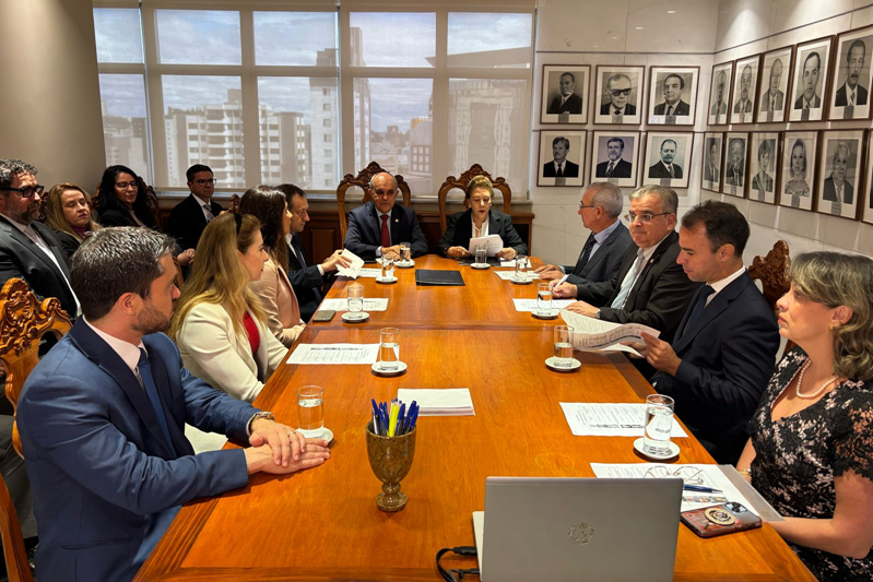 Foto das primeiras audiências. Mesa com muitas pessoas que representavam os familiares e a empresa.
