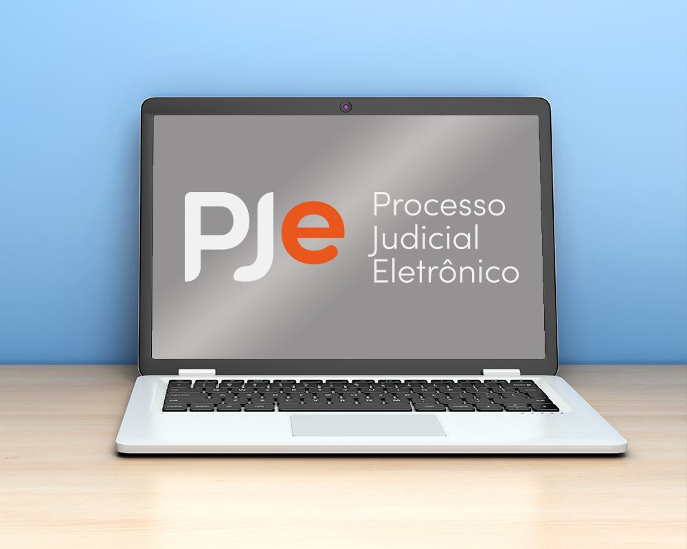 Notebook sobre a mesa com logo do PJe na tela.